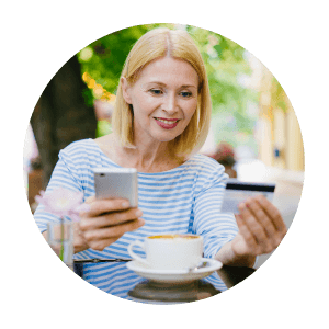 Γυναίκα με πρεσβυωπία σε εξωτερική καφετέρια, με καφέ, κρατάει ένα κινητό τηλέφωνο και προσπαθεί να διαβάσει τα ψηφία της πιστωτικής της κάρτας